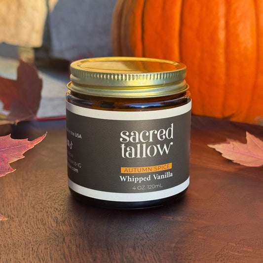 Jar of 'sacred tallow' whipped vanilla on a wooden surface with pumpkins and leaves in the background
